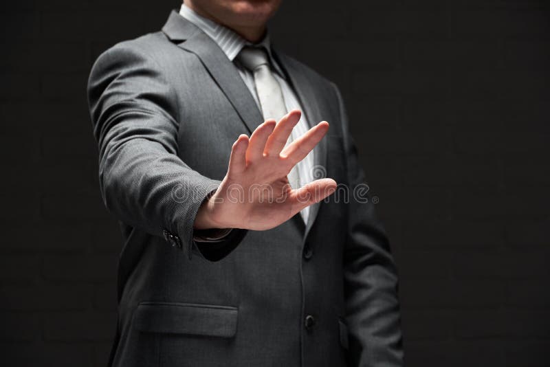 Ritratto di un uomo d'affari che mostra una palma di mano vestita di grigio sfondo di un abito scuro