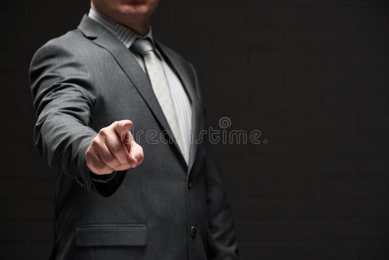Ritratto di un uomo d'affari con un dito in fronte vestito di costume grigio sfondo di parete scuro