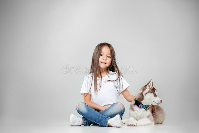 Ritratto di una bambina allegra divertendosi con il cucciolo del husky siberiano sul pavimento allo studio fotografia stock libera da diritti Ritratto di una bambina allegra divertendosi con il cucciolo del husky siberiano sul pavimento allo studio fotografia stock libera da diritti