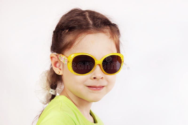 Ritratto di una bambina sveglia sorridente con gli occhiali da sole immagine stock libera da diritti Ritratto di una bambina sveglia sorridente con gli occhiali da sole immagine stock libera da diritti