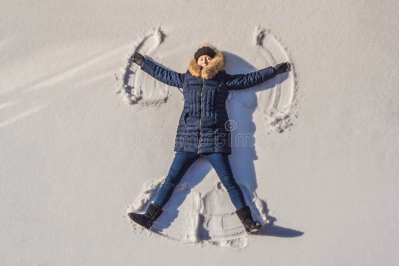 Ritratto di una bella ragazza sdraiata su un lago ghiacciato di neve che solleva e getta le braccia e le gambe creando fotografia stock libera da diritti Ritratto di una bella ragazza sdraiata su un lago ghiacciato di neve che solleva e getta le braccia e le gambe creando fotografia stock libera da diritti
