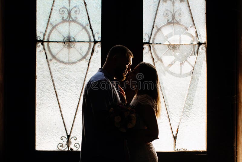 Ritratto di una coppia romantica in una lampadina da una finestra o da una porta, siluetta di una coppia in una entrata con una l fotografia stock Ritratto di una coppia romantica in una lampadina da una finestra o da una porta, siluetta di una coppia in una entrata con una l fotografia stock