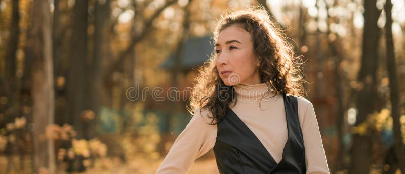 Ritratto di una donna che cammina nel parco autunnale felice umore e moda stile moda e capelli marroni ricci e lunghi immagine stock