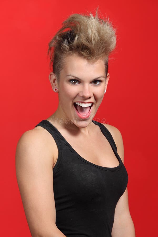 Portrait of a fashion punk hair style woman excited on a red background. Portrait of a fashion punk hair style woman excited on a red background