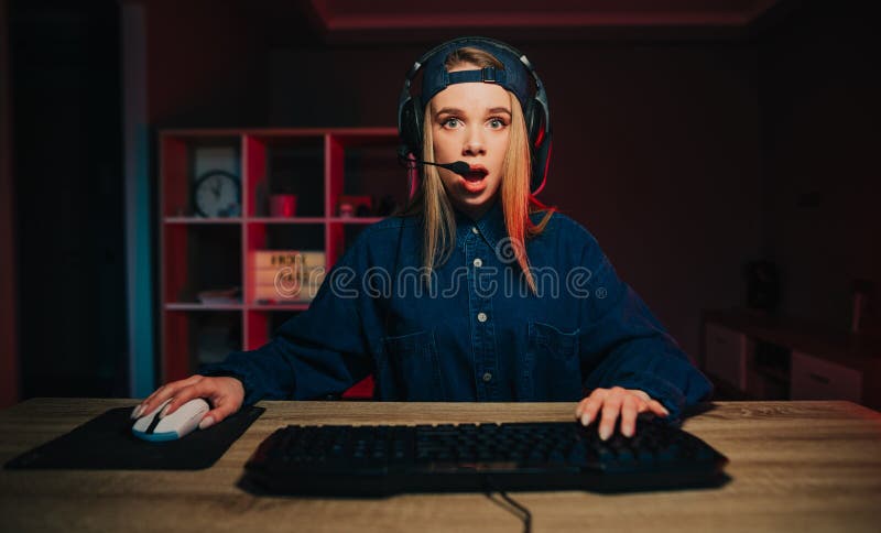 Ritratto di una donna scioccata che scorre in cuffia giocando a casa al computer e guardando la telecamera con faccia scioccata fotografie stock libere da diritti