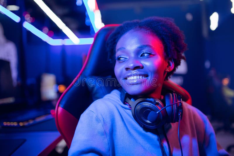 Ritratto di una giovane donna africana giocatore professionista che gioca online con un computer neon color fotografie stock