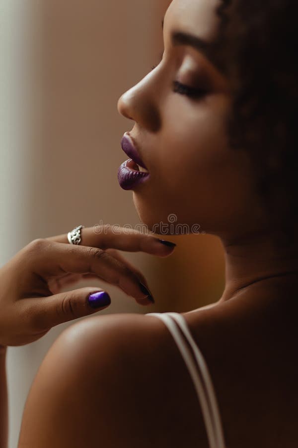 Ritratto di una giovane donna afroamericana con le labbra piene di una bellissima donna nera ricciola con trucco brillante e unghi