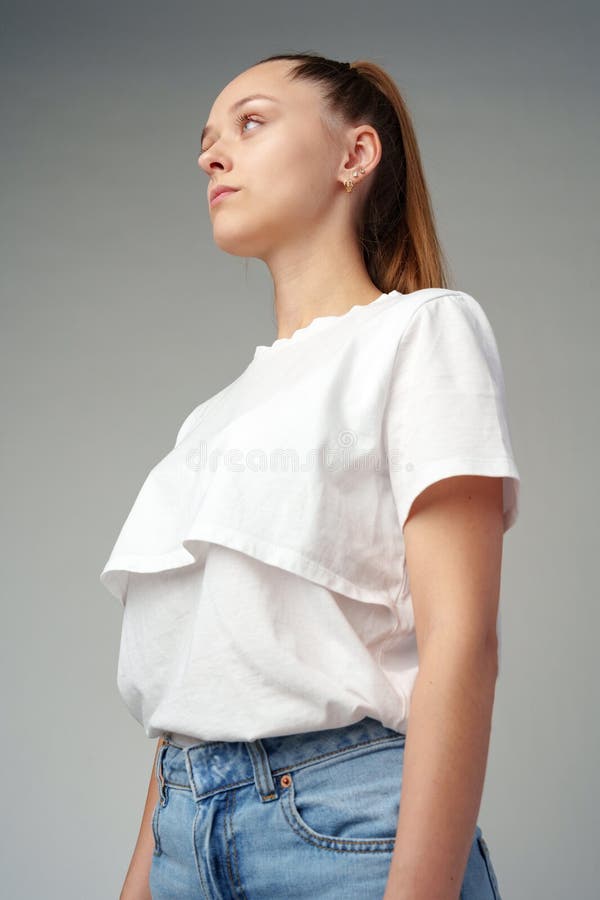 Ritratto di una giovane donna in camicia bianca sullo sfondo grigio fotografia stock