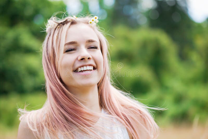 Ritratto di una ragazza che ride con i capelli rosa con una corona di margherite, ravvicinata fotografia stock Ritratto di una ragazza che ride con i capelli rosa con una corona di margherite, ravvicinata fotografia stock