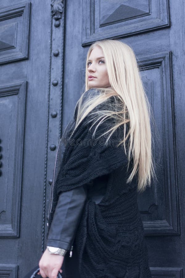 Ritratto di una ragazza con capelli biondi lunghi davanti alla grande retro entrata principale fotografia stock libera da diritti Ritratto di una ragazza con capelli biondi lunghi davanti alla grande retro entrata principale fotografia stock libera da diritti