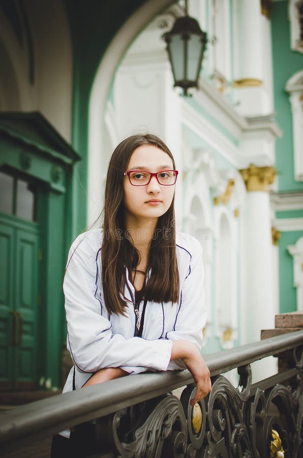 Ritratto di una ragazza graziosa con i vetri sui precedenti di bella vecchia costruzione fotografia stock libera da diritti Ritratto di una ragazza graziosa con i vetri sui precedenti di bella vecchia costruzione fotografia stock libera da diritti