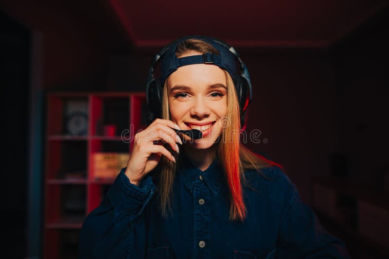 Ritratto di una ragazza ottimista che gioca a casa al computer e comunica con un microfono con un sorriso sulla faccia fotografia stock