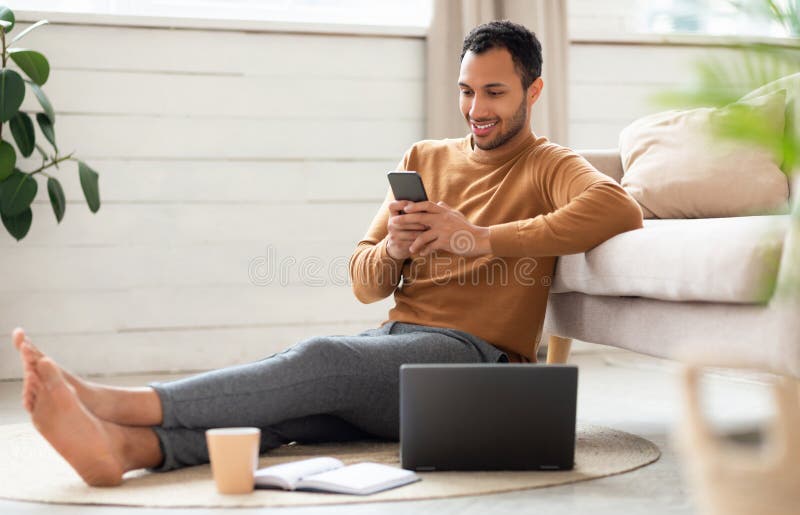 Ritratto di uomo sorridente che usa smartphone e pc a casa immagini stock
