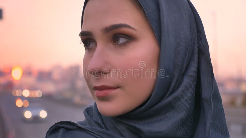 Ritratto di vista laterale del primo piano di giovane fronte femminile attraente nel hijab che guarda in avanti con la città urba fotografie stock libere da diritti Ritratto di vista laterale del primo piano di giovane fronte femminile attraente nel hijab che guarda in avanti con la città urba fotografie stock libere da diritti