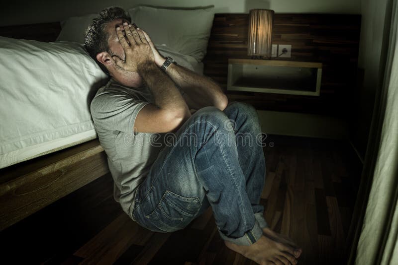 Ritratto domestico drammatico di giovane uomo solo disperato e depresso che si siede sul pavimento della camera da letto che grid fotografia stock libera da diritti Ritratto domestico drammatico di giovane uomo solo disperato e depresso che si siede sul pavimento della camera da letto che grid fotografia stock libera da diritti