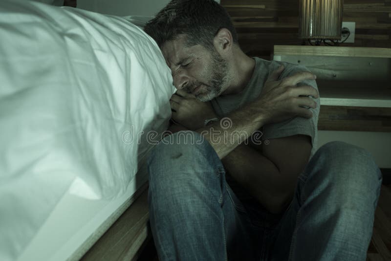 Ritratto domestico drammatico di giovane uomo solo disperato e depresso che si siede sul pavimento della camera da letto che grid fotografia stock libera da diritti Ritratto domestico drammatico di giovane uomo solo disperato e depresso che si siede sul pavimento della camera da letto che grid fotografia stock libera da diritti
