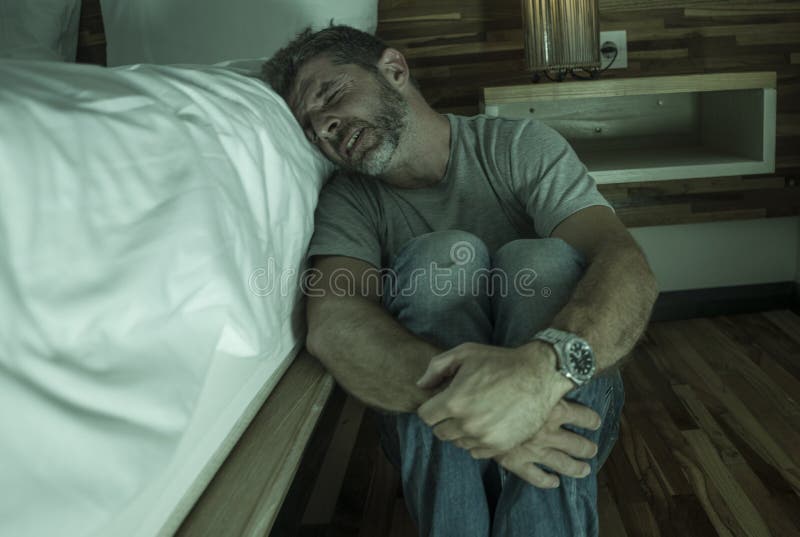 Ritratto domestico drammatico di giovane uomo solo disperato e depresso che si siede sul pavimento della camera da letto che grid immagini stock libere da diritti Ritratto domestico drammatico di giovane uomo solo disperato e depresso che si siede sul pavimento della camera da letto che grid immagini stock libere da diritti