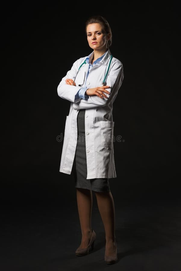Ritratto integrale della donna seria di medico su fondo nero immagini stock libere da diritti Ritratto integrale della donna seria di medico su fondo nero immagini stock libere da diritti