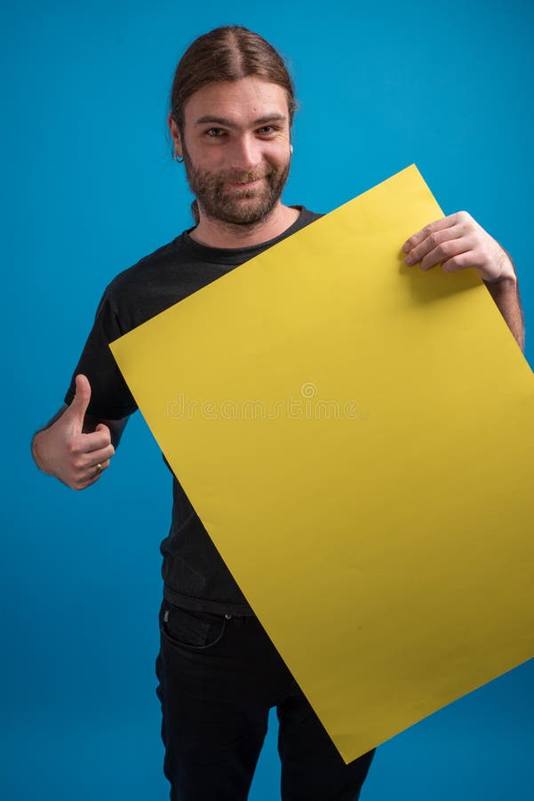 Ritratto maschio che visualizza segno giusto mentre tenendo un cartone giallo del manifesto immagine stock libera da diritti Ritratto maschio che visualizza segno giusto mentre tenendo un cartone giallo del manifesto immagine stock libera da diritti