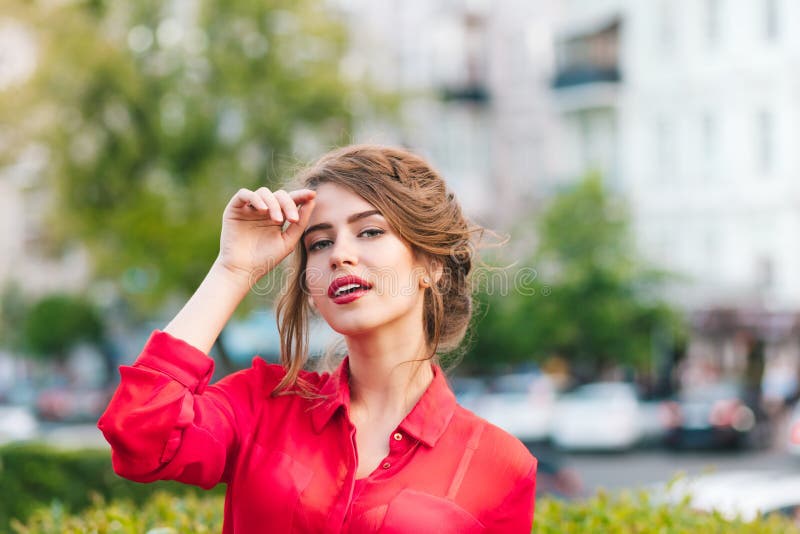Ritratto orizzontale del primo piano della condizione graziosa della ragazza nel parco Indossa la blusa rossa e l'acconciatura pi fotografie stock libere da diritti Ritratto orizzontale del primo piano della condizione graziosa della ragazza nel parco Indossa la blusa rossa e l'acconciatura pi fotografie stock libere da diritti