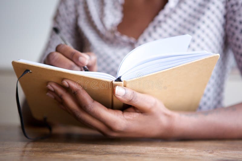 Ritratto parziale dell'autore femminile nero a casa che scrive in giornale immagini stock libere da diritti