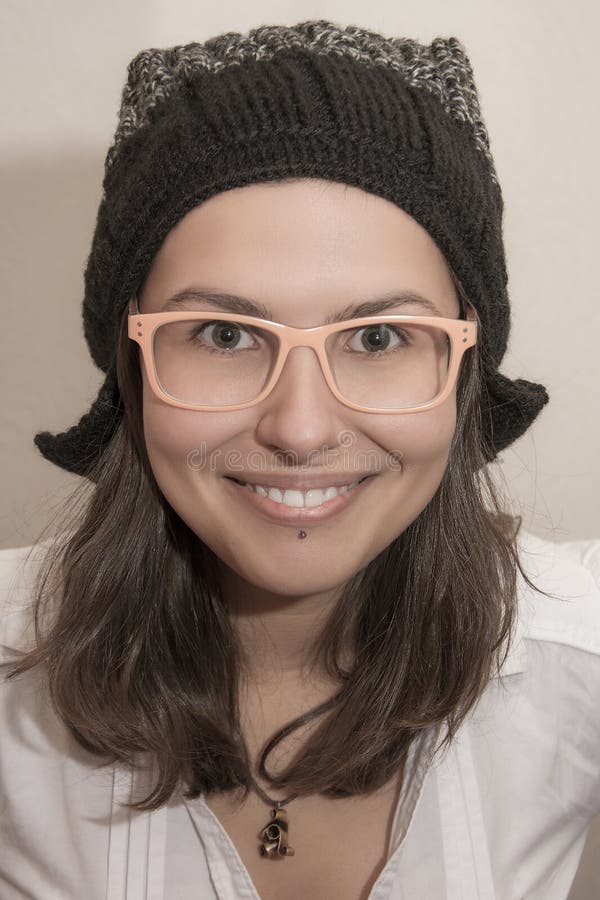 Ritratto sorridente divertente della ragazza con i vetri del cappello e di estate di inverno immagini stock libere da diritti Ritratto sorridente divertente della ragazza con i vetri del cappello e di estate di inverno immagini stock libere da diritti
