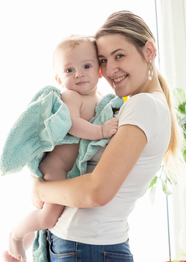 Ritratto tonificato della madre felice che abbraccia il suo neonato coperto in b fotografia stock libera da diritti Ritratto tonificato della madre felice che abbraccia il suo neonato coperto in b fotografia stock libera da diritti