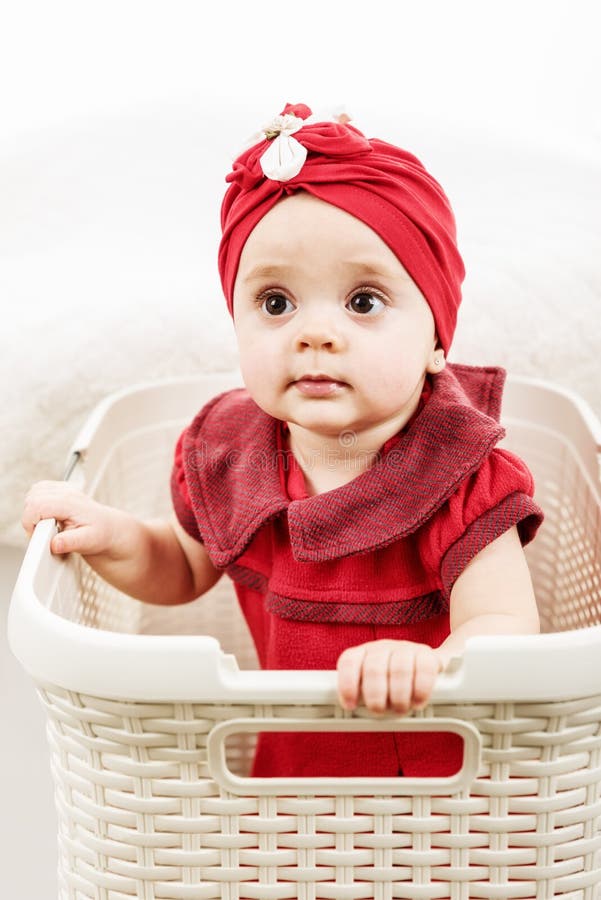 Ritratto verticale della bambina di 1 anno dentro il canestro di lavanderia fotografie stock Ritratto verticale della bambina di 1 anno dentro il canestro di lavanderia fotografie stock