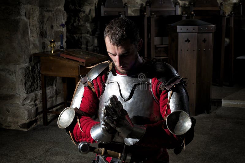 Ritter-Kneeling On His-Knie mit gebeugtem Kopf und den betenden Händen stockfotografie Ritter-Kneeling On His-Knie mit gebeugtem Kopf und den betenden Händen stockfotografie