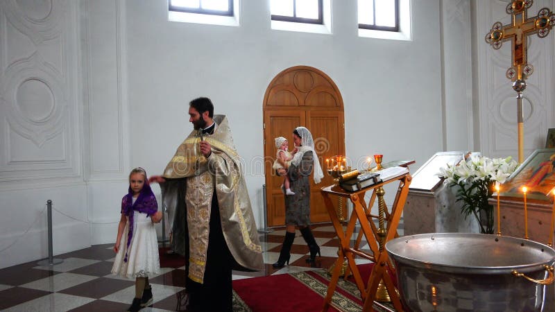 Ritual of baptism in the Orthodox Church with a cross in hands