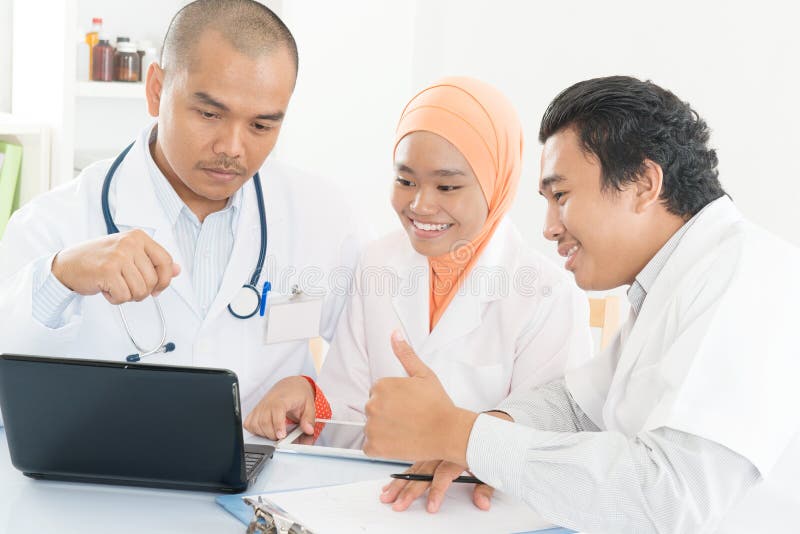 Riunione asiatica del gruppo di medici all'ufficio ed ai pollici dell'ospedale su immagine stock libera da diritti Riunione asiatica del gruppo di medici all'ufficio ed ai pollici dell'ospedale su immagine stock libera da diritti