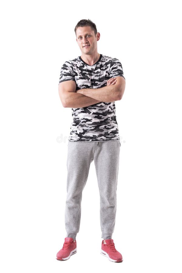 Riuscito sportivo muscolare sicuro negli sweatpants e nel sorridere della camicia dell'esercito immagine stock libera da diritti Riuscito sportivo muscolare sicuro negli sweatpants e nel sorridere della camicia dell'esercito immagine stock libera da diritti
