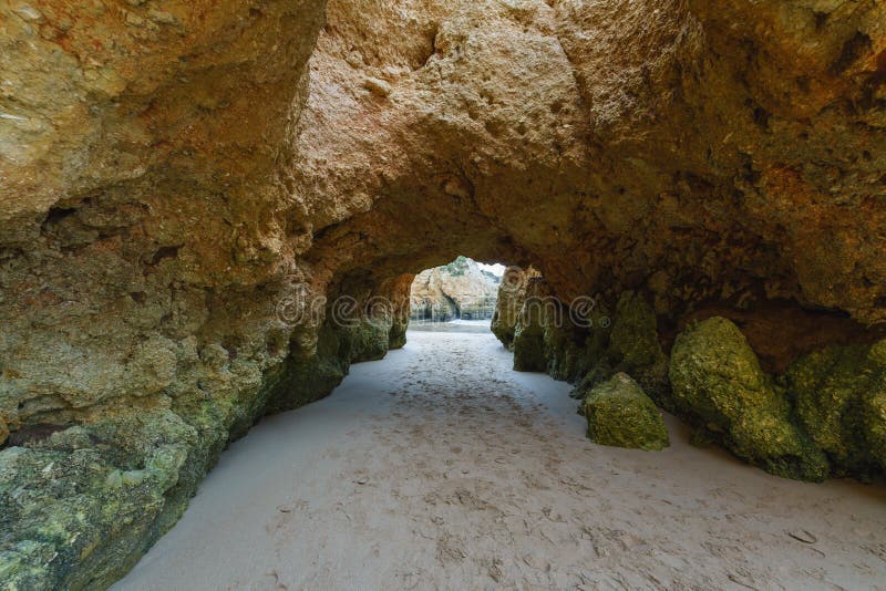 Rugged shoreline with rocky formations, a sandy beach, and a dramatic overcast sky, Algarve, Portugal. Rugged shoreline with rocky formations, a sandy beach, and a dramatic overcast sky, Algarve, Portugal