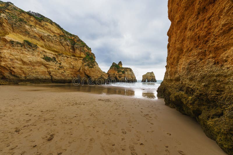 Rugged shoreline with rocky formations, a sandy beach, and a dramatic overcast sky. Rugged shoreline with rocky formations, a sandy beach, and a dramatic overcast sky