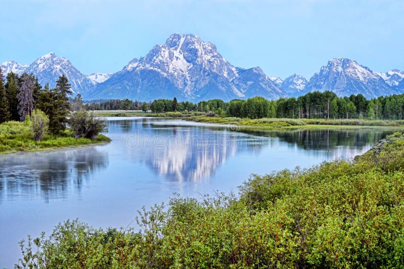 A river in Colorado reflects snow capped mountains.