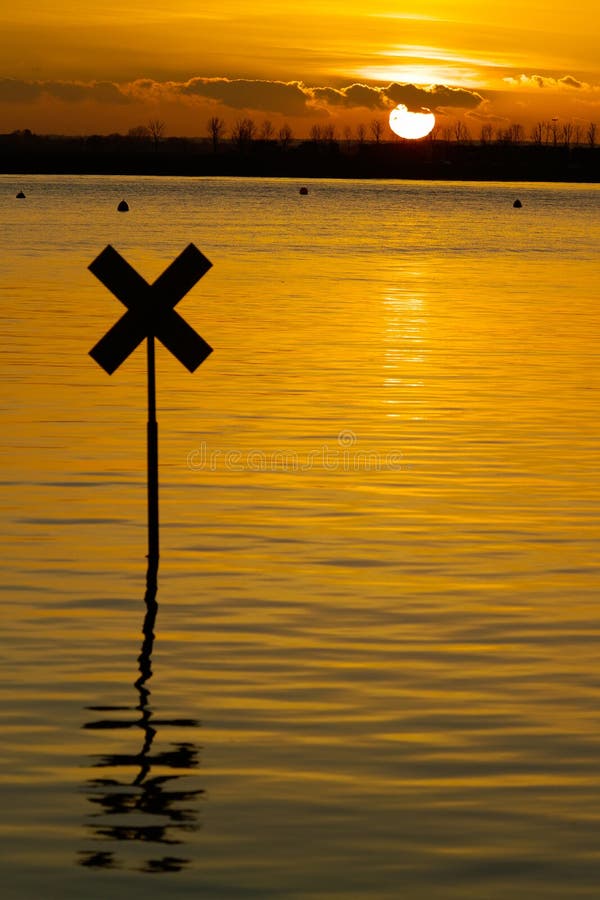 River marker silhouetted against the setting sun