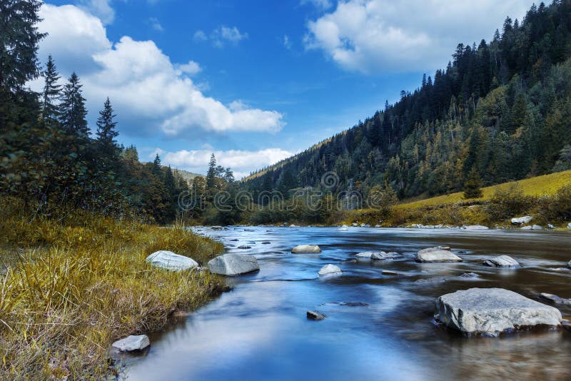 River in mountains with rocks, yellow grass on riverside. Autumn