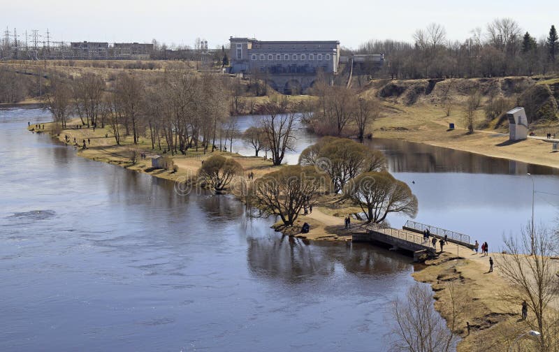 River Narva on border of Russia and Estonia. Narva, Estonia - May 1, 2017: people are walking along riverside Narva river dividing Russia and Estonia stock photos River Narva on border of Russia and Estonia. Narva, Estonia - May 1, 2017: people are walking along riverside Narva river dividing Russia and Estonia stock photos