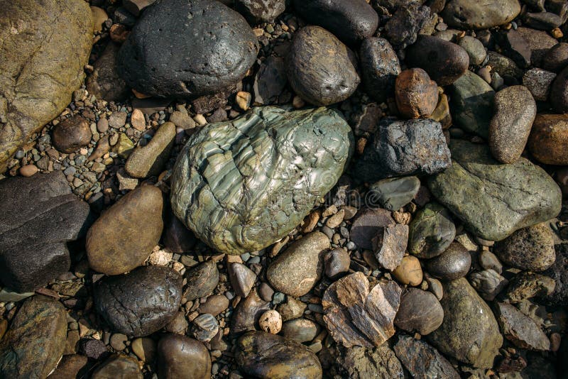 River stones glisten in the sun. One large grey-green cobblestones of little colorful pebbles. Concept of the stone background stock photo River stones glisten in the sun. One large grey-green cobblestones of little colorful pebbles. Concept of the stone background stock photo