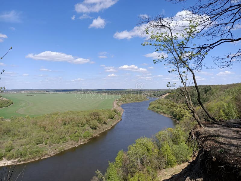 Riverbend in deep spring forestm with green trees on the bank of the river and sands under blue sky