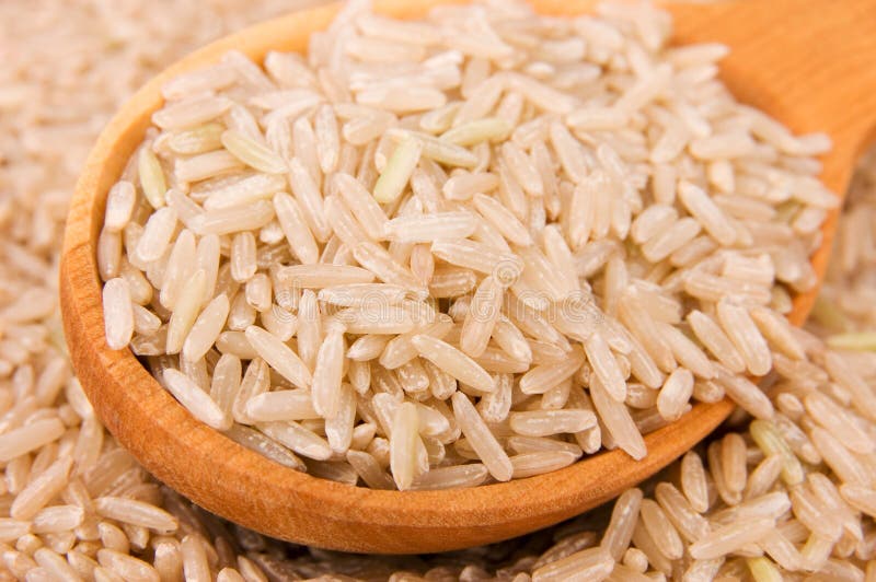 Raw brown rice in wooden spoon close-up. Raw brown rice in wooden spoon close-up