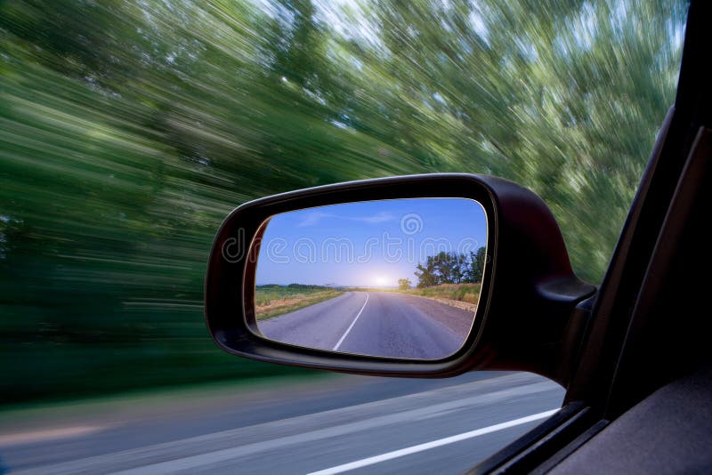 Dettagli di strada riflessa in viaggio auto vista laterale specchio con sfondo sfocato.