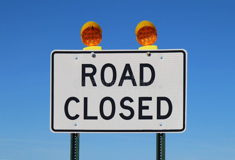 Road closed sign against a bright blue sky