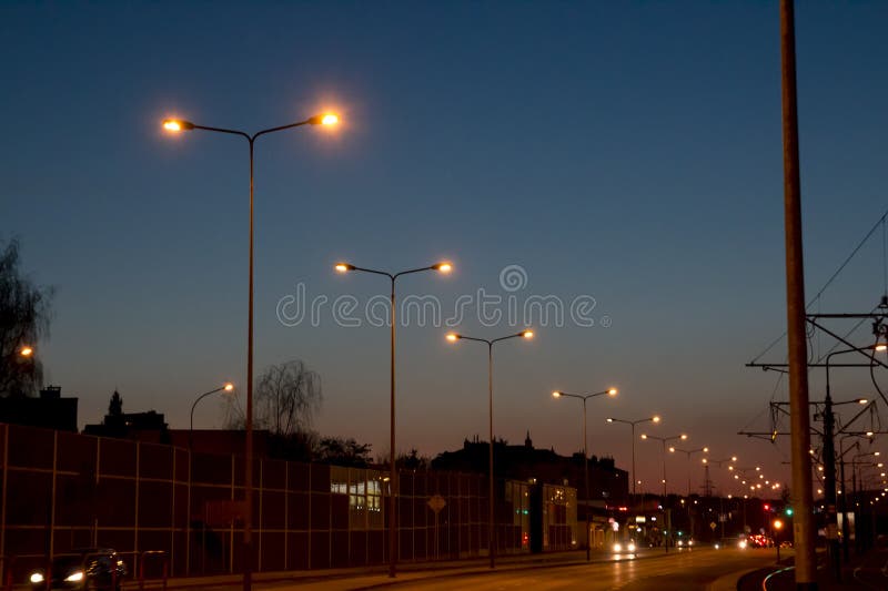 The road in the evening with cars and burning ulicni lamps, against the background of dusk and the dark blue sky