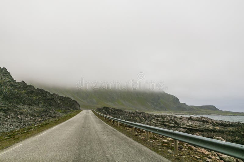 The road leading to the mountains is covered with heavy clouds stock photography