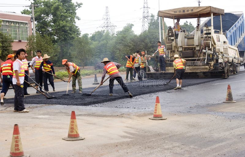 Road Construction in China. Several Chinese workers are busy constructing a new road. As economy grows,more and more roads are built in China. Location:Wuhan city of China,Time:2010/6/15.