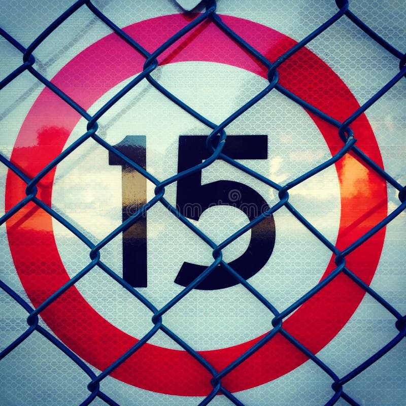 15 Road Speed Sign with Red Circle and Chain Link Fence Stock Image