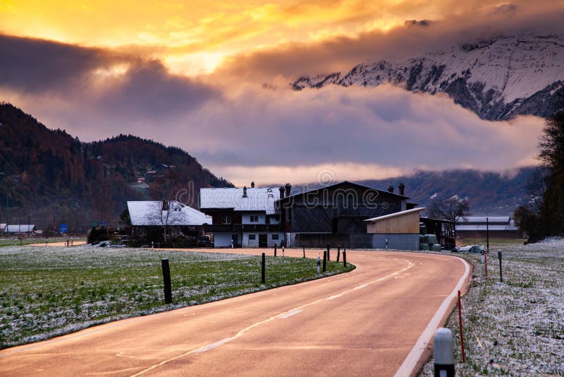 road at sunset leading to snow covered mountain peaks