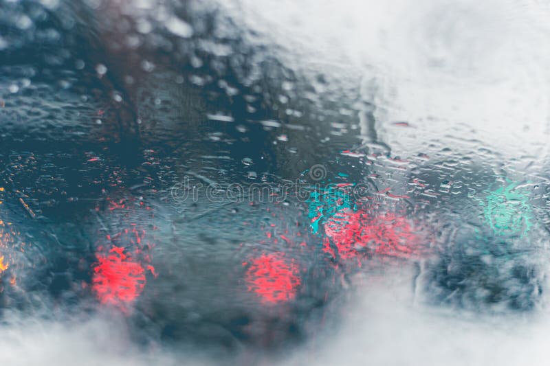 Road view through car window with rain drops and melting snow.