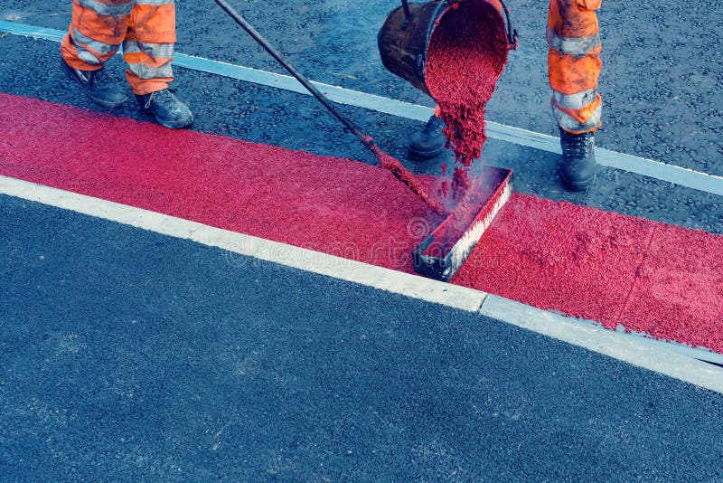 Road Workers Applying Hot Red Road Marking Paint on New Build Road